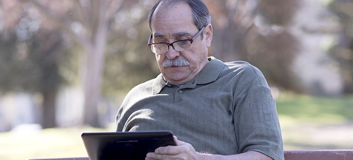 Un hombre en el parque revisando el estatus de su pedido en una tablet