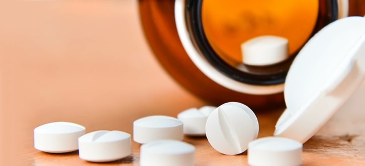 A bottle of generic medications poured out on a table 