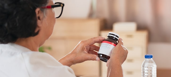 A woman reading the label of her prescription at home