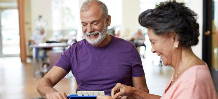 Older couple adding meds to daily pill box