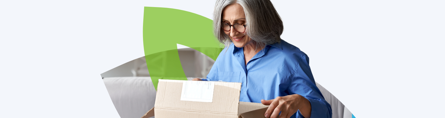 Una mujer sonriente abriendo un paquete de medicamentos recetados que le enviaron.