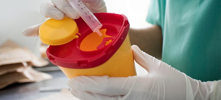 Nurse disposing a needle in appropriate container