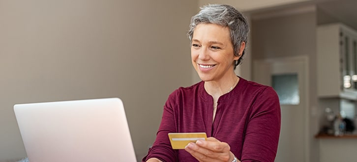 An older woman on laptop holding her credit card