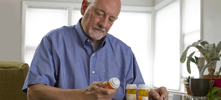 Cliente masculino de CenterWell Pharmacy revisando sus medicamentos en casa