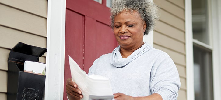 Mujer mirando un paquete pequeño que recibió en la puerta de su casa